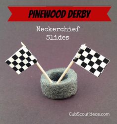 two flags sticking out of a rock with the words pinewood derby next to it