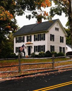 a large white house sitting on the side of a road next to a tree filled street