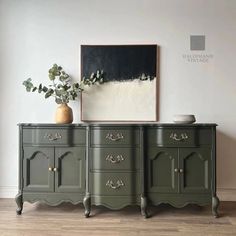 a green dresser with two vases and a painting on the wall