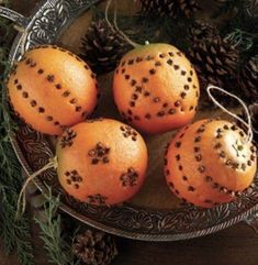 three oranges are sitting on a plate with pine cones