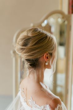 the back of a woman's head wearing a white wedding dress with a veil