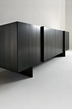 an empty room with black cabinets on the floor and white walls in front of it