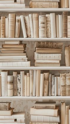 many books are lined up on shelves in a room with wallpaper and floral designs