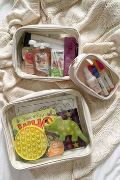 two plastic containers filled with toys on top of a white blanket next to each other