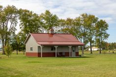 a red and white barn sitting on top of a lush green field next to trees