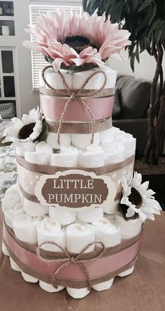 a diaper cake that is stacked high on top of each other and has a pink flower in the center