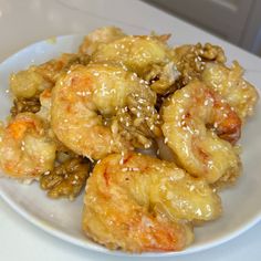 a white plate topped with fried shrimp and sesame seeds