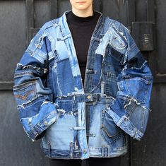 a woman standing in front of a black door wearing a jean jacket with holes on it