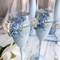 two wine glasses decorated with blue flowers and pearls are sitting next to each other on a table