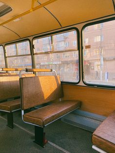 the inside of a bus with two benches and windows on both sides, in front of some buildings