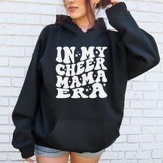 Stay warm, cozy, and stylish as you support your favorite cheerleader with our In My Cheer Mama Era hoodie! This hoodie is made from a super soft and cozy material that will envelop you in warmth and comfort. Whether you're cheering on your cheerleader at a local game or a national competition, this hoodie is the perfect choice to keep you warm and stylish throughout the event. Show your true cheer mama spirit while enjoying the luxurious comfort of this hoodie! Current processing time is 5-10 b Competitive Cheer, Cheerleading, Stay Warm, Sweatshirts