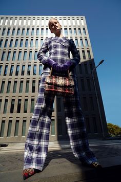 a mannequin dressed in plaid clothes stands on the sidewalk