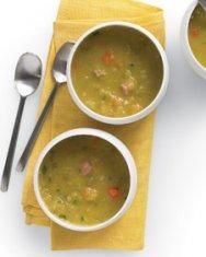 two white bowls filled with soup on top of a yellow napkin next to silver spoons