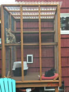 a cat sitting in a cage on top of a wooden table next to a blue chair