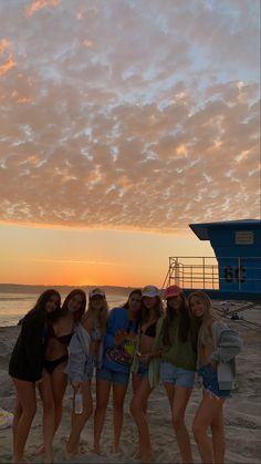 a group of young women standing on top of a sandy beach next to the ocean