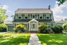 a house with green grass and trees in the front yard