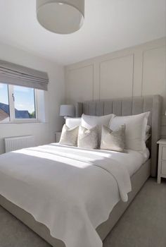 a bed with white sheets and pillows in a bedroom next to a window that looks out onto the ocean