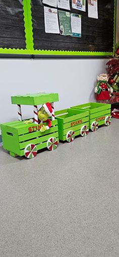 a green wagon filled with candy canes sitting on top of a floor next to a christmas tree