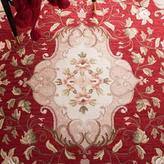 a red rug with white and green flowers on it