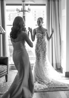 two women standing in front of a window and one is brushing her teeth while the other looks on