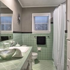 a bathroom with two sinks and green tile on the walls, along with a shower curtain