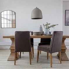 a dining room table with chairs and vases on it's side, in front of a white brick wall