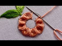 a pair of scissors sitting next to a piece of yarn and a green leaf on top of it