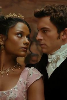 a man in a tuxedo standing next to a woman wearing a tiara