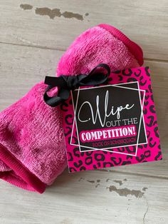 a pink mitt with a black bow on it that says wipe out the competition