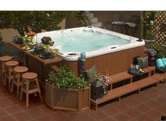 an outdoor hot tub surrounded by potted plants and stools on a patio area