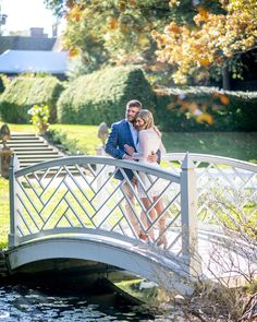 a man and woman are standing on a bridge near the water while holding each other