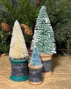 three small christmas trees sitting on top of a wooden table