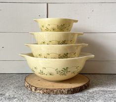 four bowls stacked on top of each other in front of a white wall and wood