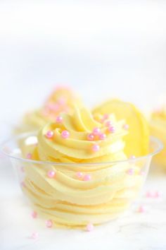 some yellow cupcakes with pink sprinkles in a glass bowl