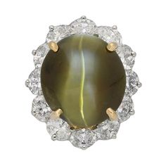 a ring with a large green stone surrounded by white and yellow diamond trimmings