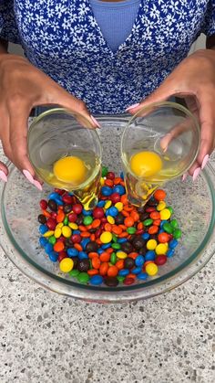 a woman is pouring eggs into a bowl filled with candy