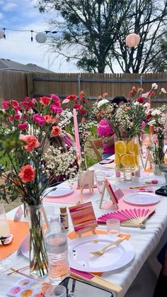 a table set up with plates and flowers in vases on top of the tables