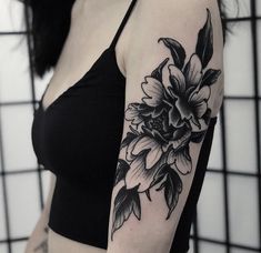 a black and white photo of a woman's arm with flowers tattooed on it