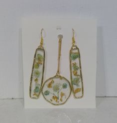 This jewelry set is made with real baby's breath flowers! They are dyed to be a greenish and blue hue then pressed flat. It also has little flakes of gold to compliment the flowers. They are sealed in resin acrylic to have them last forever! The drop length of the earrings are 2" and the necklace length is 18" Nickel Free Gold Botanical Jewelry, Nickel-free Gold Botanical Jewelry, Nickel-free Botanical Gold Jewelry, Gold Flower Resin Earrings, Gold Pressed Flower Earrings For Mother's Day, Green Botanical Drop Earrings Jewelry, Gold Brass Jewelry With Pressed Flowers, Delicate Green Jewelry With Birth Flower, Handmade Gold Flower Earrings For Mother's Day