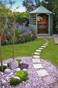 a small garden with rocks, grass and flowers in the background is a gazebo