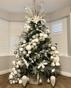 a white christmas tree with silver ornaments and snowflakes