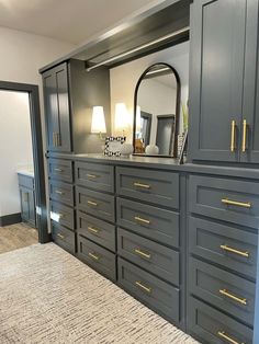 a large gray dresser with gold handles in a living room next to a mirror and lamp