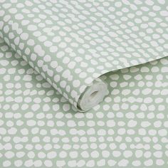 a green and white polka dot wallpaper with a roll of toilet paper on it