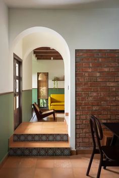 an archway leads to the living room and dining area in this modern home with brick walls