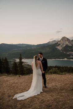 a bride and groom standing on top of a mountain