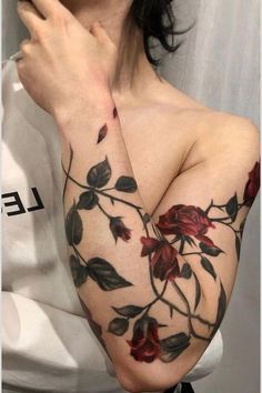 a woman's arm with flowers on it, and the arms are covered in tattoos