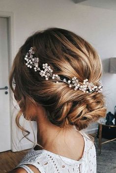 a woman wearing a hair comb with flowers on it's head and pearls in her hair