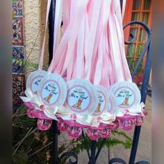 pink and white plates are hanging from a wrought iron stand with ribbons on it, in front of a house