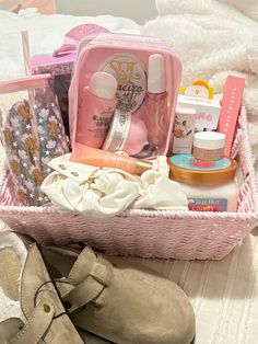 a pink basket filled with personal care items next to a pair of shoes on a bed