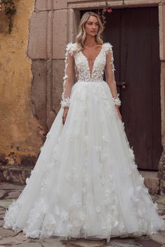 a woman standing in front of a doorway wearing a wedding dress with flowers on it